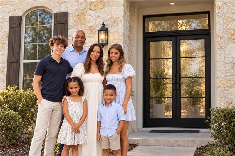 The family behind OMG Steel Doors standing in front of black steel double entry doors at their Austin home