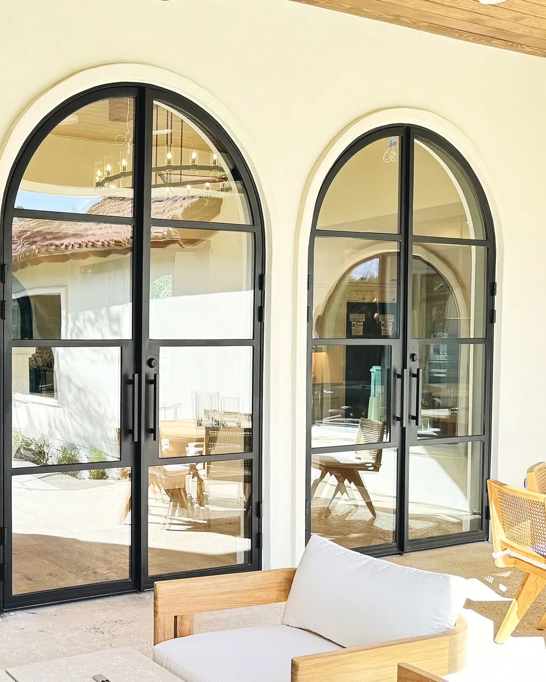 Custom round-top black steel French doors opening to a covered patio
