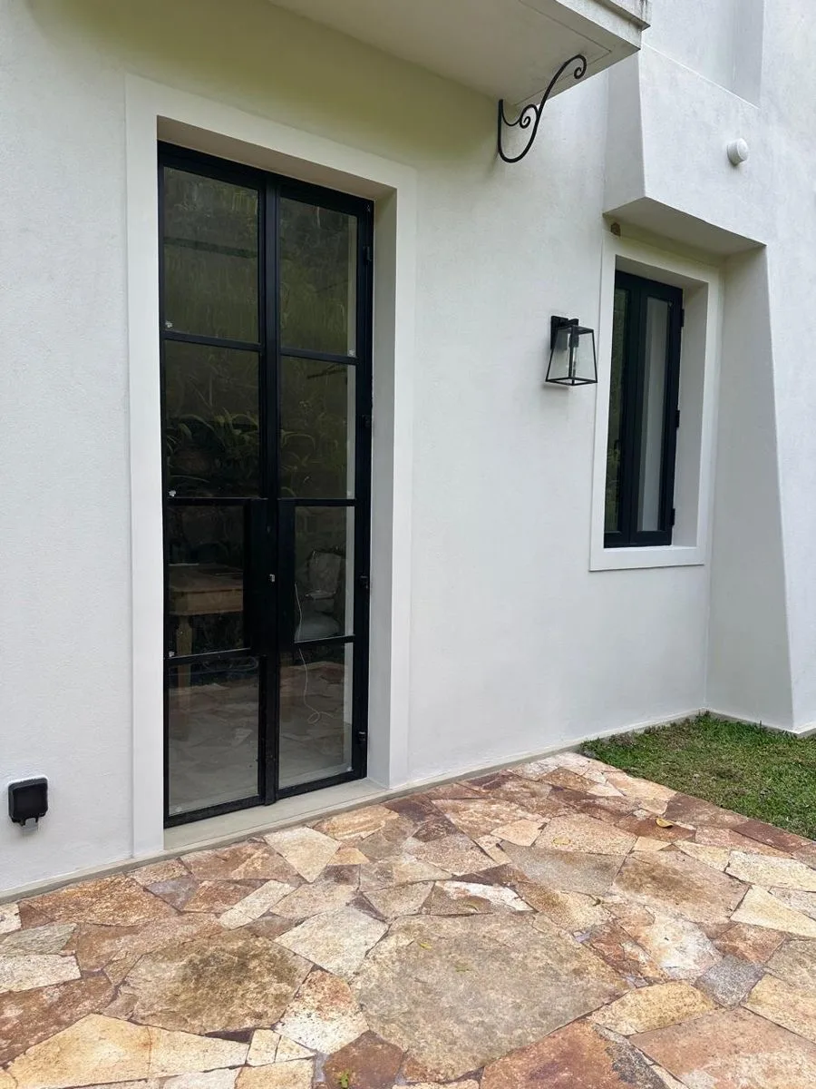 Narrow black steel and glass French doors opening onto a stone patio