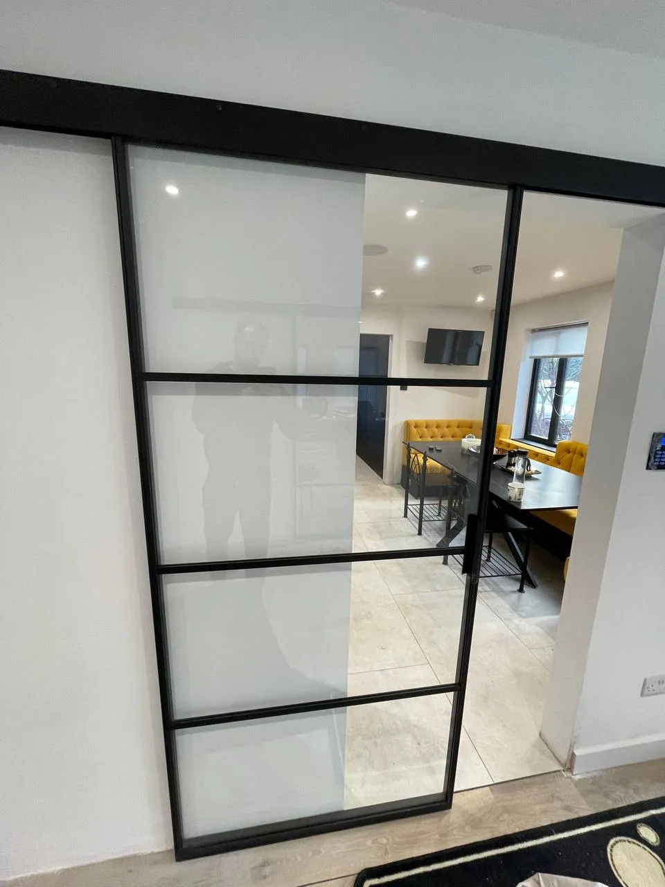 Steel framed sliding glass door on a surface track dividing two interior rooms Steel framed sliding glass door on a surface track dividing two interior rooms