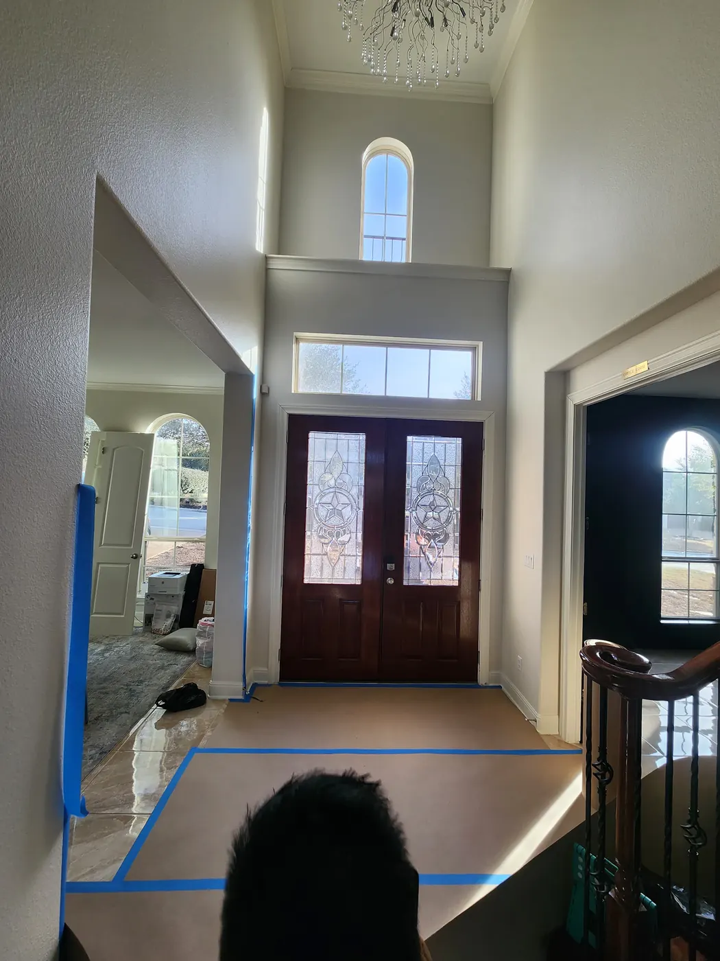 Two-story foyer of a Dripping Springs home looking toward the old wood entry doors