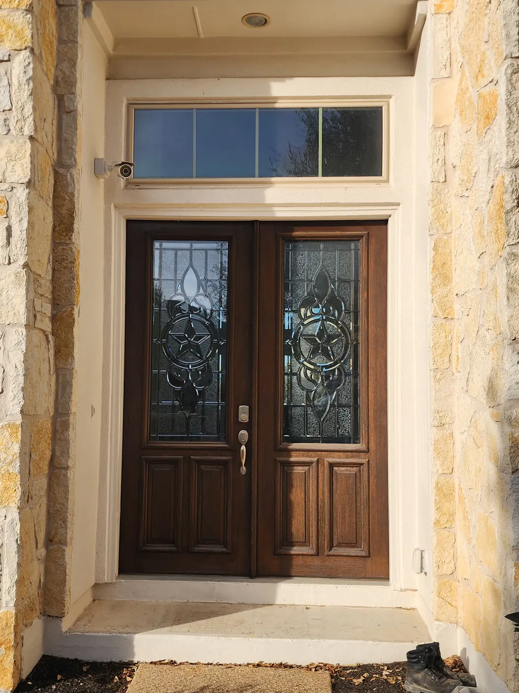 Original stained wood double entry doors on a stone home in Dripping Springs before steel door replacement