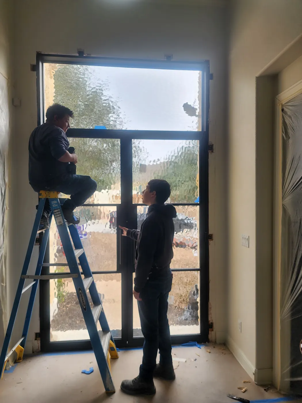 Installers plumbing and anchoring a steel door frame during an Austin area installation