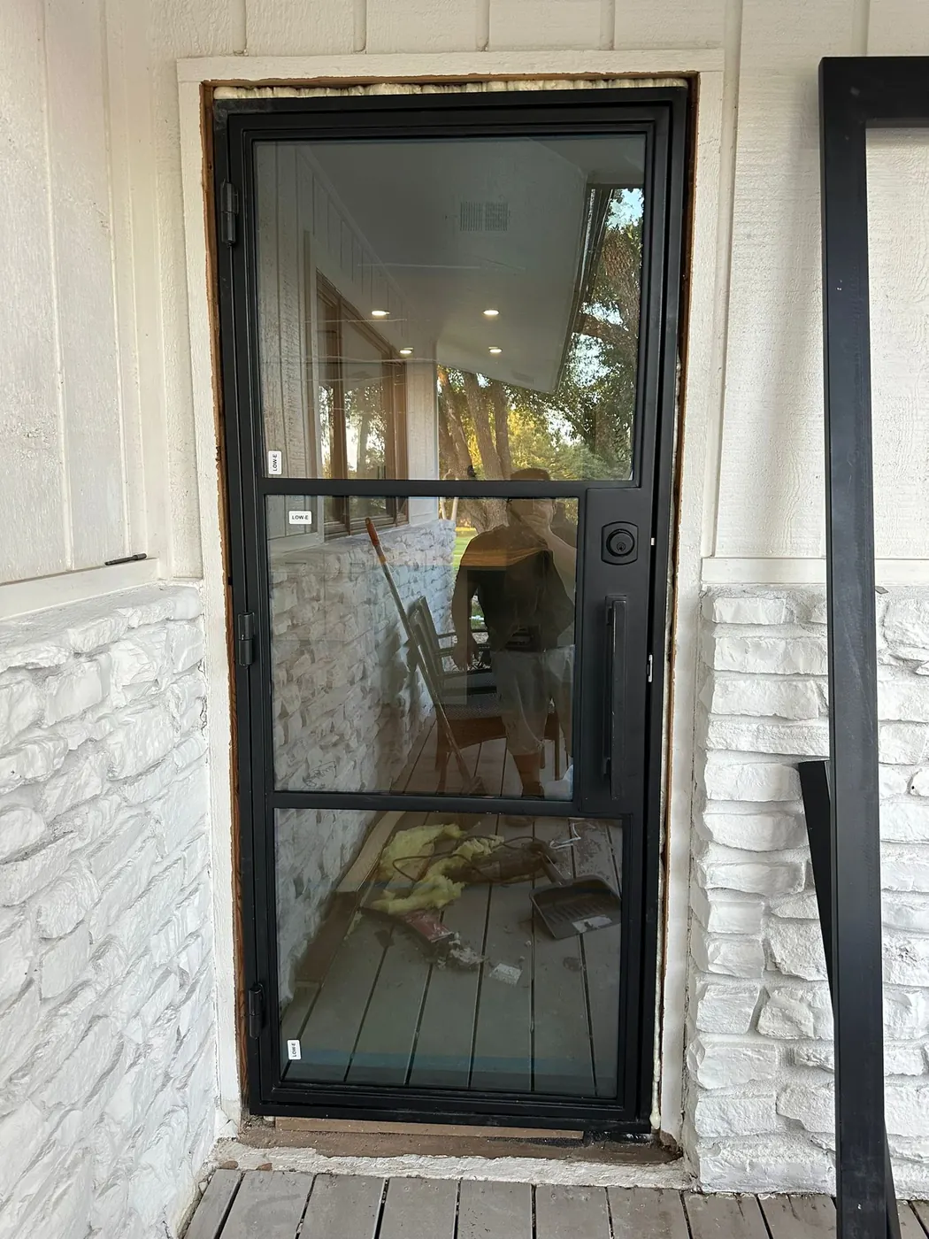 Black steel entry door with divided lites set into white brick at a Lakeway residence