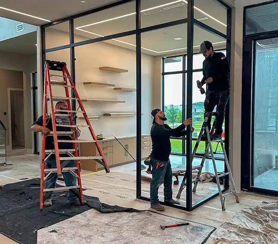 Installation crew positioning a steel-framed glass door unit inside a home